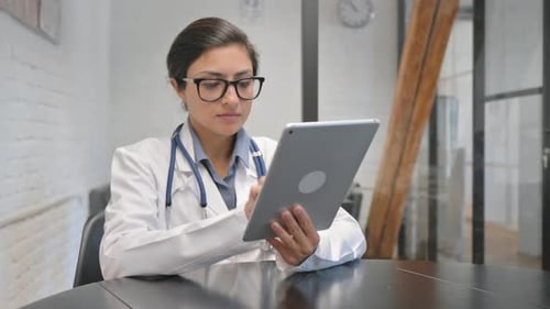 Doctor Uses Tablet Device at Office Table