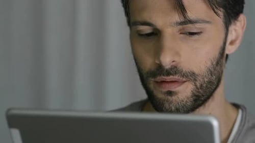 Man using tablet device in dim indoor lighting