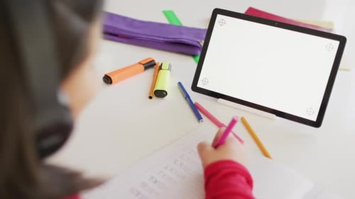 Child Studies With Tablet and Headphones at Table
