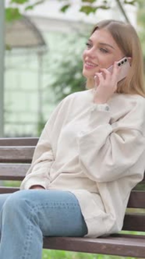 Smiling Woman Chatting on Cell Phone on Park Bench