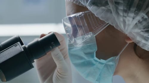 Scientist Looking Through Microscope in Laboratory Setting