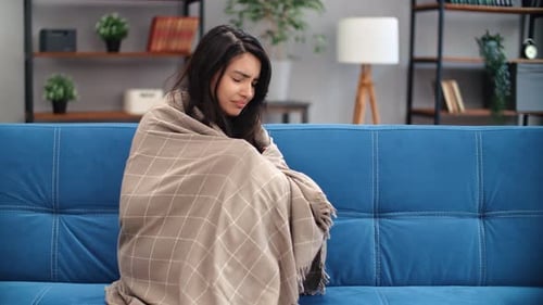 Sick Woman Coughing on a Sofa Wrapped in Blanket