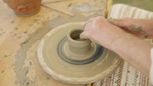 Gros plan d'un potier formant un vase à partir d'argile humide sur un volant.