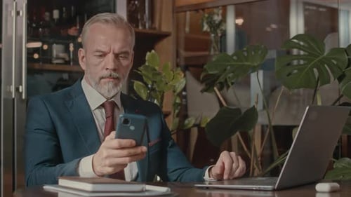 Portrait of Mature Businessman Sitting at Restaurant Table
