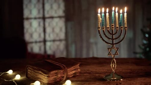 Hanukkah Menorah Lights on Wooden Table with Book