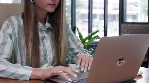 Engaged in Freelancing a Ukrainian Woman of a Young Age Operates Her Computer Within a Cafe Setting