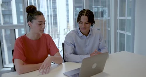 Two Young Adult Business Colleagues Engaged in Discussion in Office Meeting room