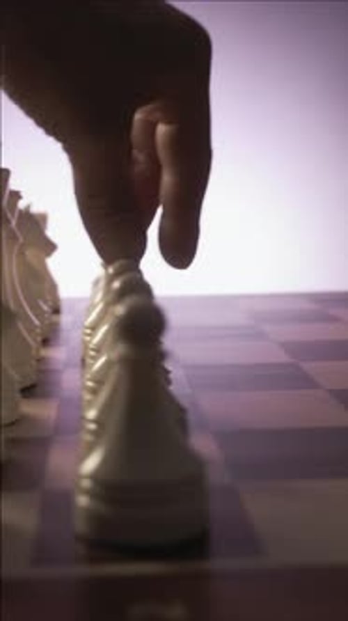 A Man Moves a White Pawn on a Chessboard