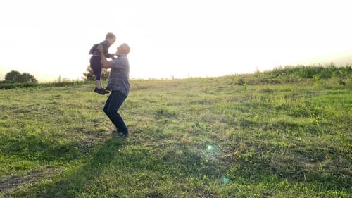 Father and Son Spending Time Together in Gold Lights of Sun at Meadow