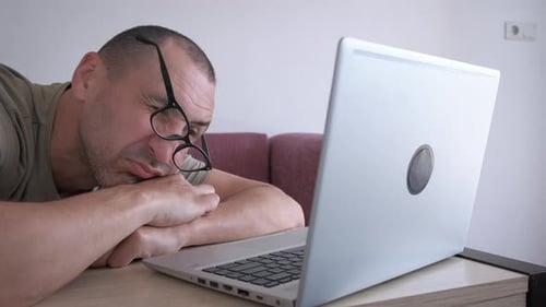 Man Sleeping at Desk with Laptop and Glasses