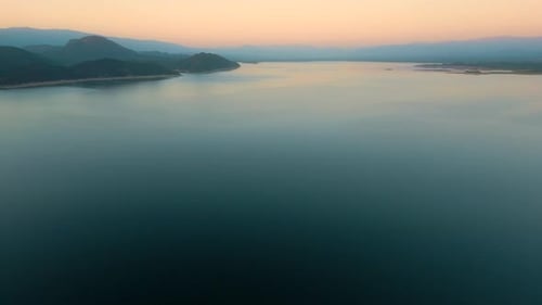 Aerial drone flying over a lake, water dam, with mountains at sunrise. Beautifull dreamy landscape