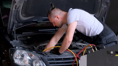 Worker Fixing Car Under Hood in Garage Using Automotive Tools