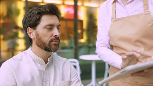 Bearded Man Ordering Food via Digital Tablet with Waitress at Cafe