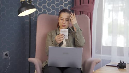 Woman Reviews Receipts at Home with Laptop
