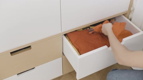 Hands Removing Rust Colored Shirt from a Drawer