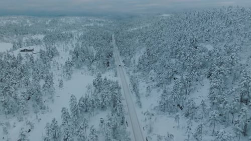Drone footage of an EV driving in beautiful snowy landscape in Norway with snow covered tree tops