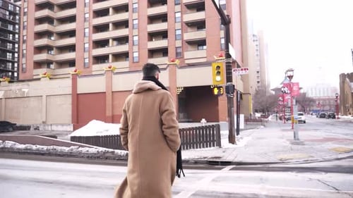 Young Man in Long Wool Coat Crossing Winter City Street at Crosswalk Adult