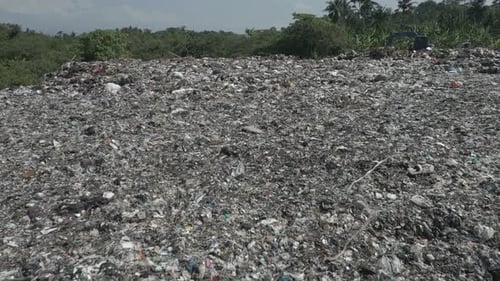 Low flyover of large garbage dump polluting green Indonesian forest