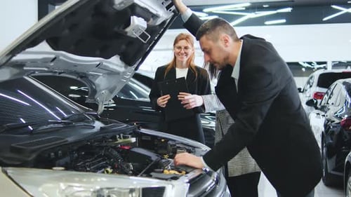 Client Inspects Engine with Saleswoman Present at Automobile Dealership During Vehicle Consultation