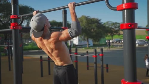 Athlete Man Does Pull Ups on Horizontal Bar Outdoors