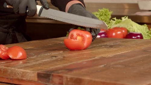 Person Slices Tomato on Wooden Cutting Board