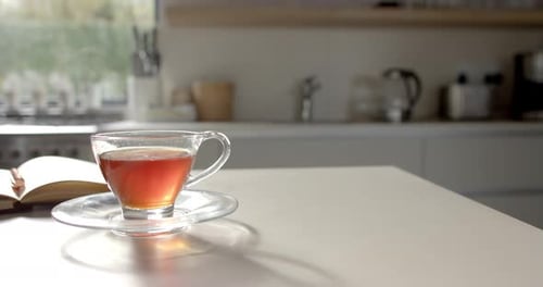 Eine Tasse Tee auf dem Tisch mit einem teilweise sichtbaren Buch