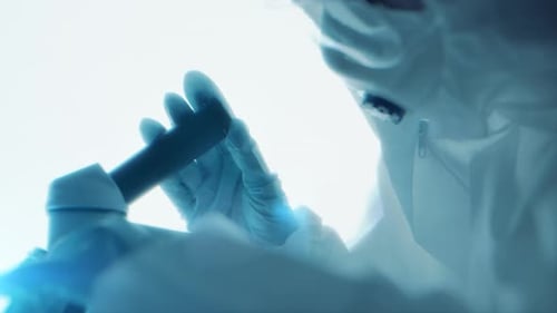 Virologist Scientist in Protective Suit Using Microscope in Biohazard Laboratory for Medical