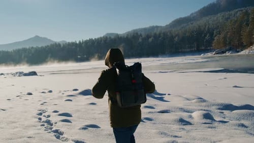Backpacker Walking Through Snowy Winter Landscape