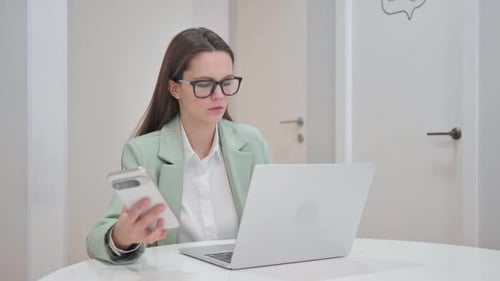 Woman Uses Smartphone in Modern Office Workspace