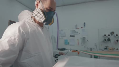 Surfbrettfabrik. Erwachsener Mann arbeitet in der Surfbrettfabrik und stellt das Surfbrett her
