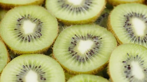 Kiwi Fruit Slices Slowly Turning on a White Background