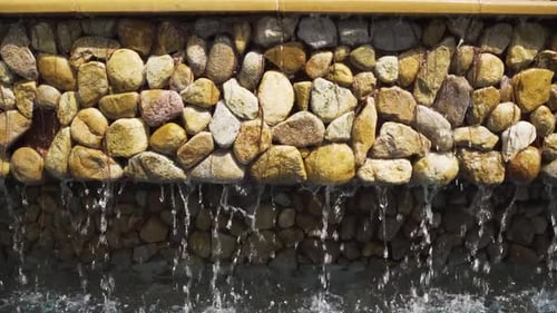 CLOSE UP Stonewall Water Feature. Water cascading Down Into A Pool