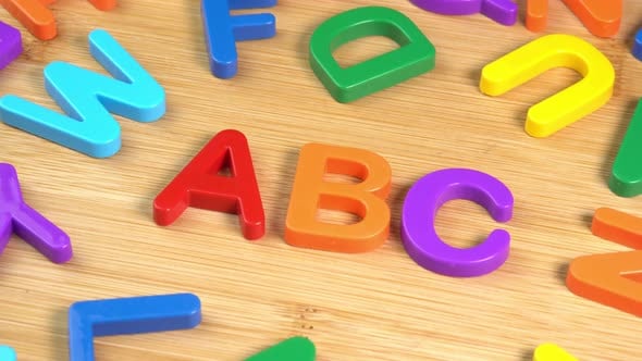 Colorful ABC Alphabet letters rotate on a wooden background. The ...