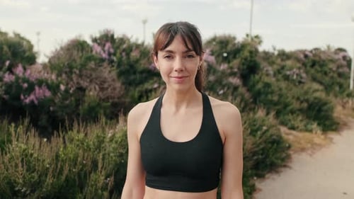 European smiled girl in sportswear against the park and trees, fit woman portrait