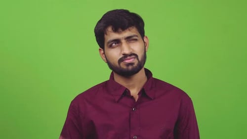 Attractive man showing thinking gesture while pointing to his forehead, isolated on green screen