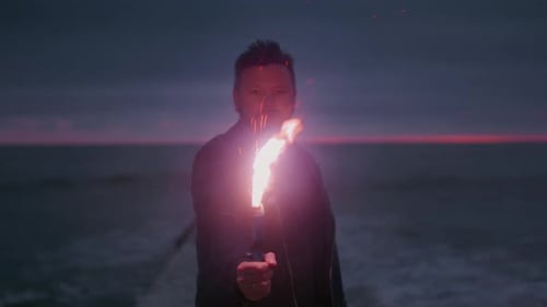 Man Holding Fire Stick on Beach at Night