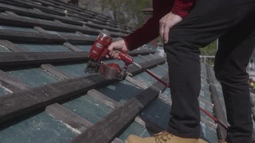 Skilled construction worker wearing yellow hard hat no safety gear pneumatic nail gun expertly secur