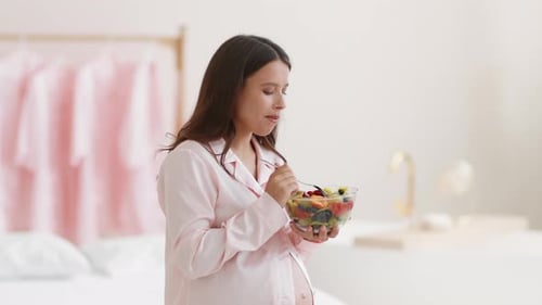 Pregnant Woman Eating Fruit Salad in Bedroom