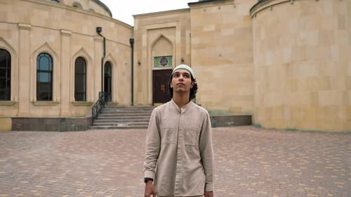portrait of a young Arab man looking into the camera against the background of Muslim mosque