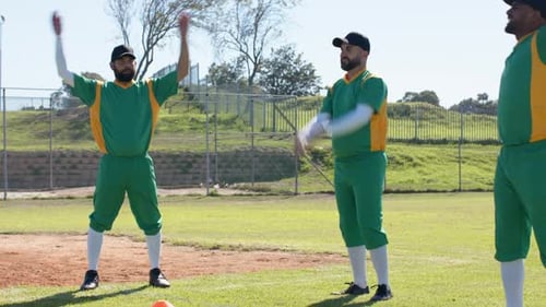 After signal Diverse male teammates in green uniforms raising and rotating arms warming up on field