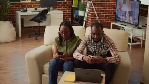 Couple Using Smartphones on Couch at Home