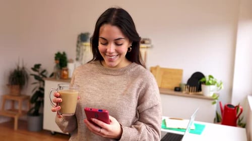 Smiling Woman Using Phone and Holding Coffee