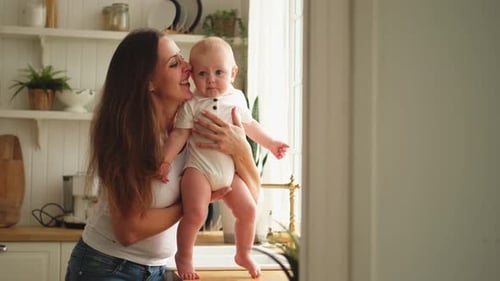 Mother Comforts Crying Infant in Kitchen