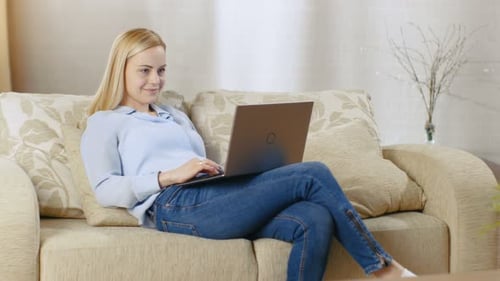 Woman with Laptop Relaxing Comfortably on the Couch