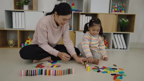 happy toddler girl and mother playing colorful wooden block toy or domino game together