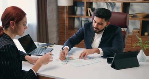 Two Business Multiracial Colleagues Discussing Documents in Office.