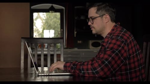 Man Typing on Laptop at Table Indoors