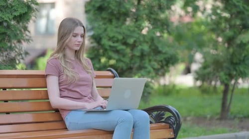 Woman Works on Laptop on Park Bench