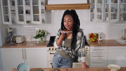Woman Smells Fresh Salad in Kitchen