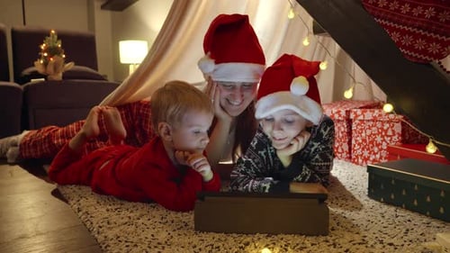 Family Wearing Santa Hats Watches Tablet